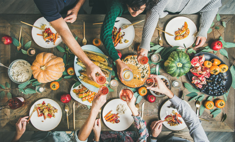 Friends clinking glasses at Thanksgiving Day with vegetarian meals