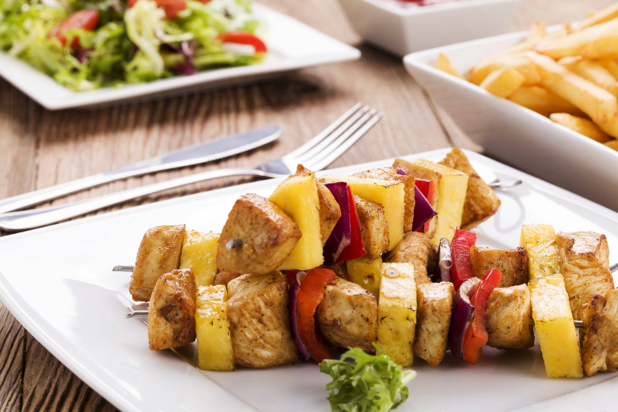 Grilled chicken skewers with pineapple, peppers and onions serve