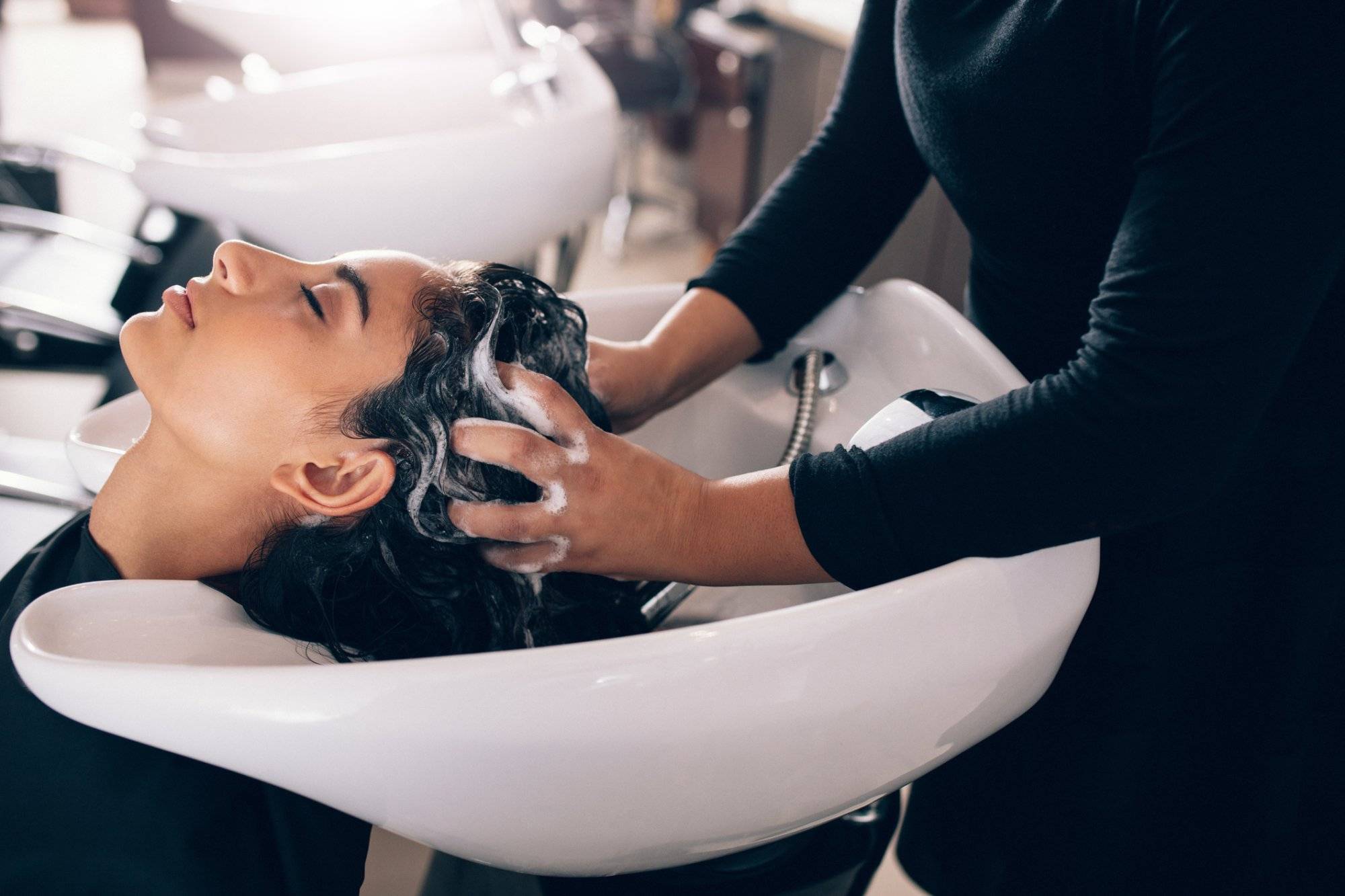 Woman getting hair shampooed at salon