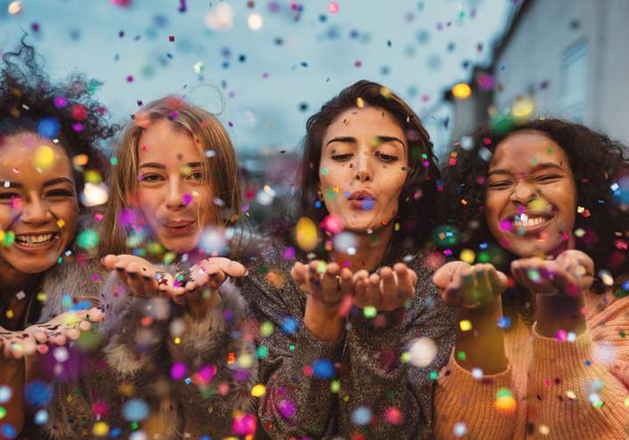 Young women blowing confetti from hands.