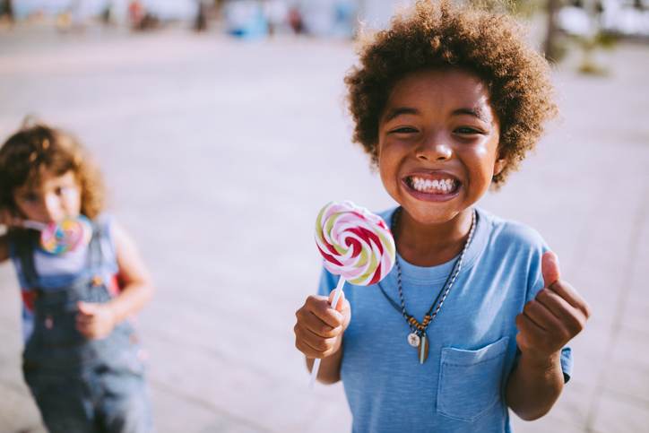 Multi-ethnic children with colorful lollipops outdoors on summer vacations Multi-ethnic children with colorful lollipops outdoors on summer vacations