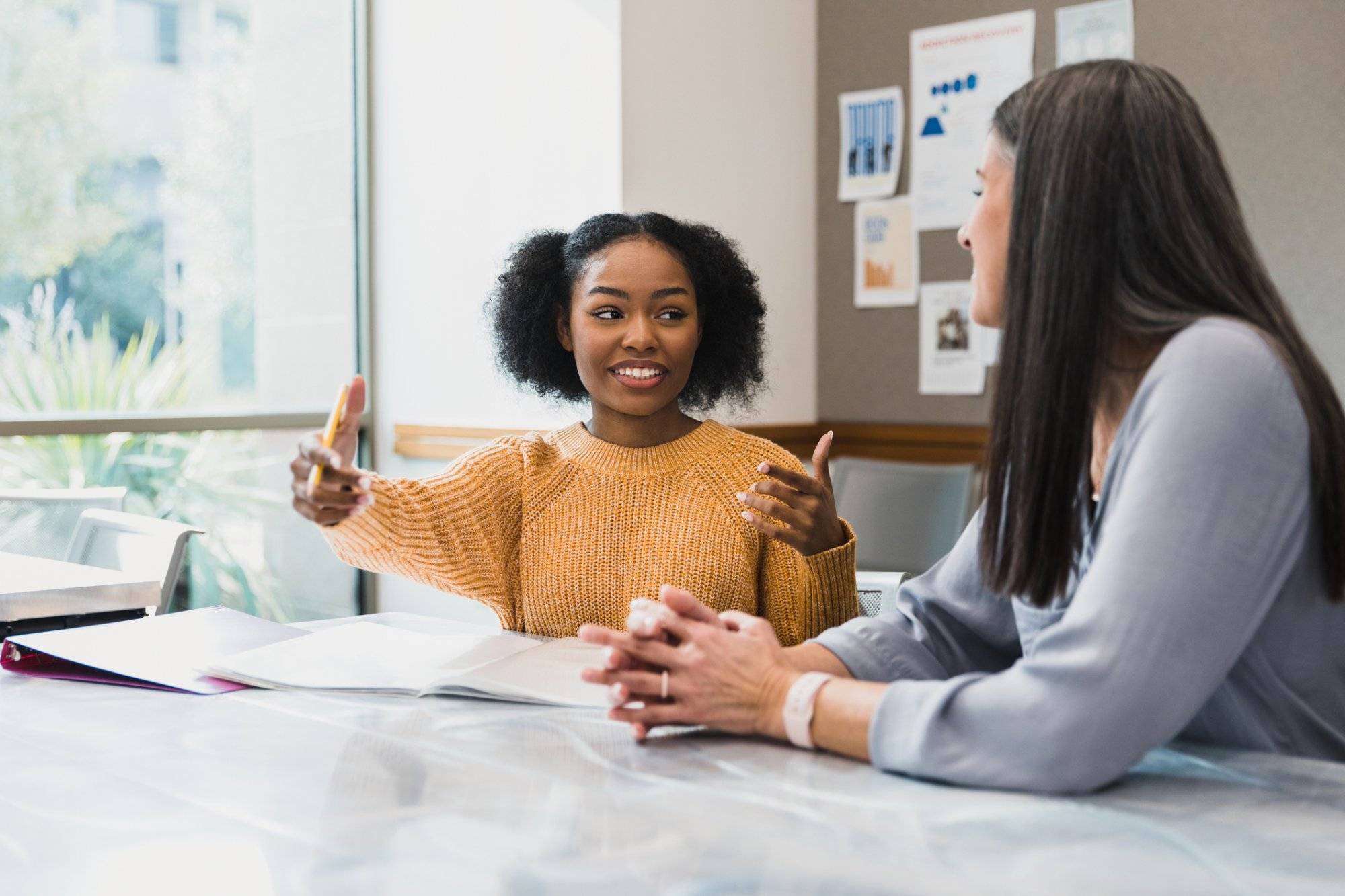 Teen girl gestures while explaining something to female teacher