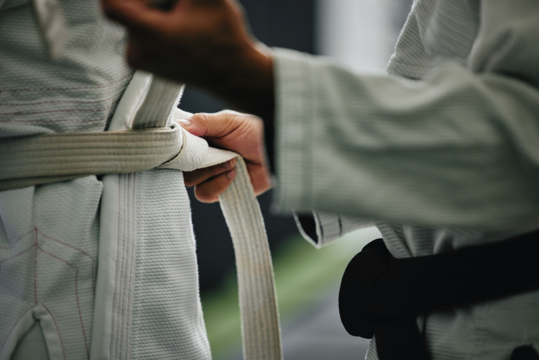 Karate learning, training and workout of a sport student and coach getting ready for a fight class. Defense expert hands tie a belt in a dojo, workout studio or wellness club about to work on fitness